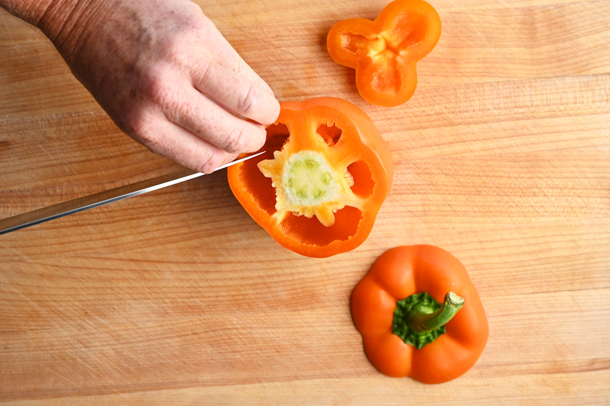Someone seeding an orange bell pepper