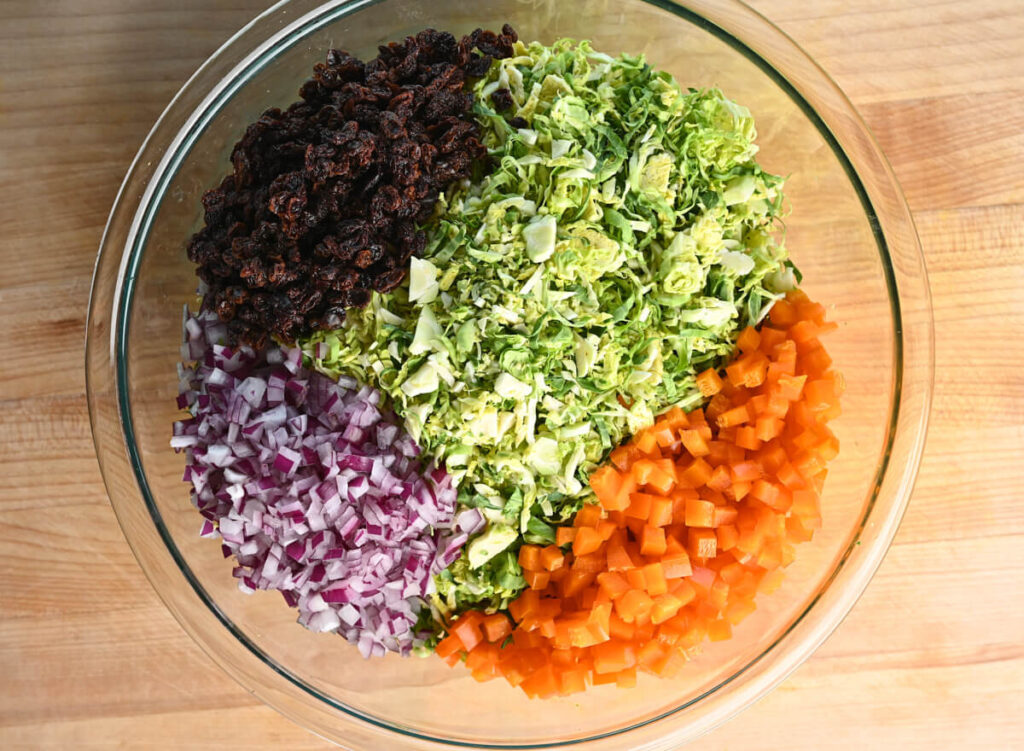 Bowl of rehydrated currants, sliced Brussels sprouts, diced bell pepper, and diced red onion.