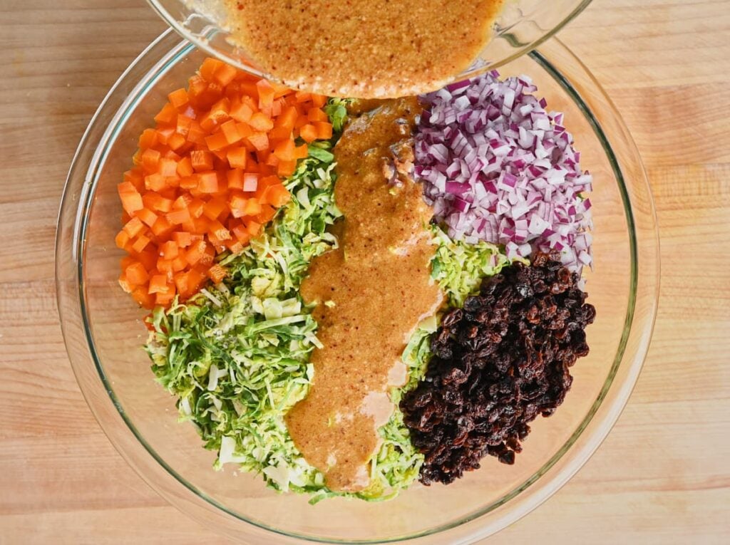 Pouring the vinaigrette over the Brussels sprouts salad.