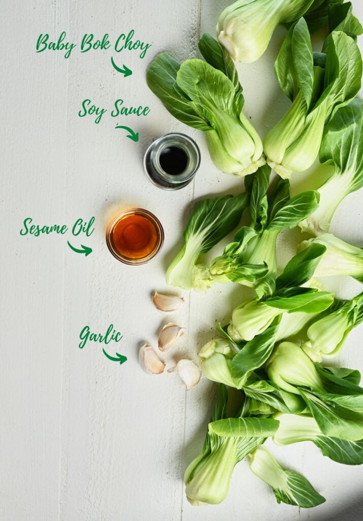 Ingredients for cooking baby bok choy, including baby bok choy, soy sauce, sesame oil, and garlic.