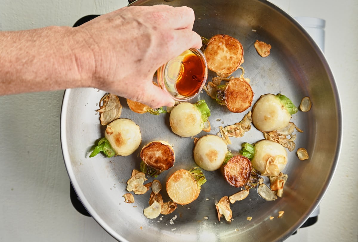 soy sauce being added to turnips and sauteed garlic