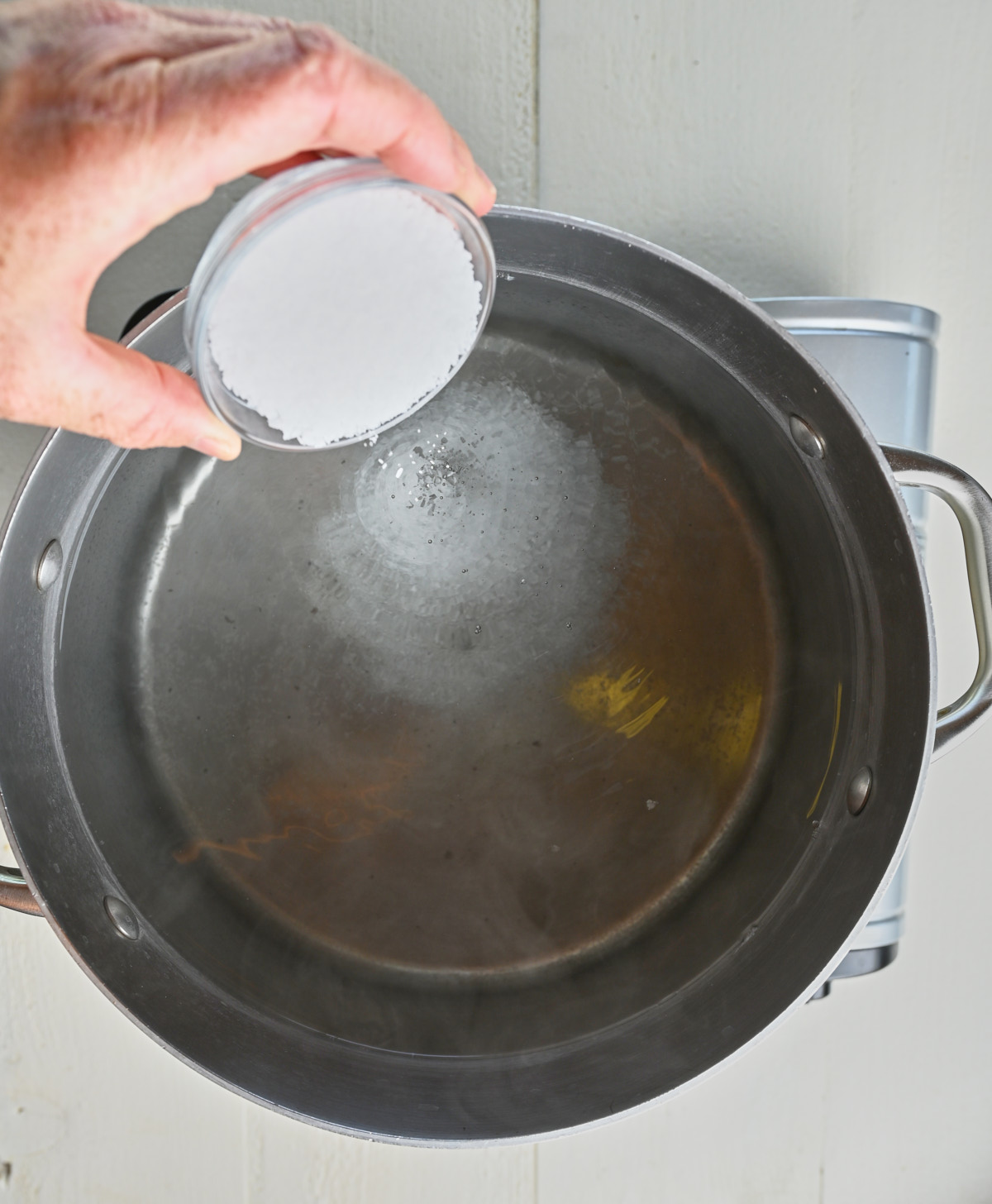 salt being put into a pot of water preparing to boil