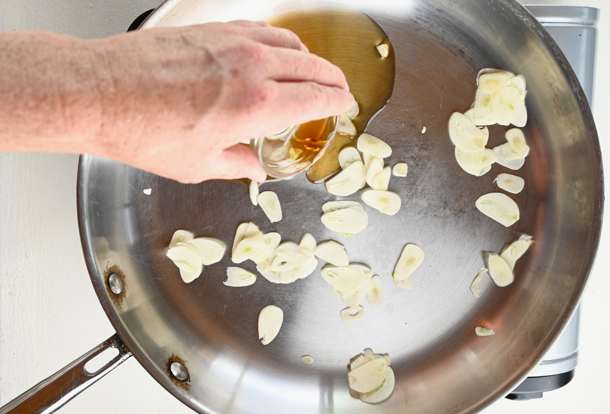 oil being poured into a pan over garlic