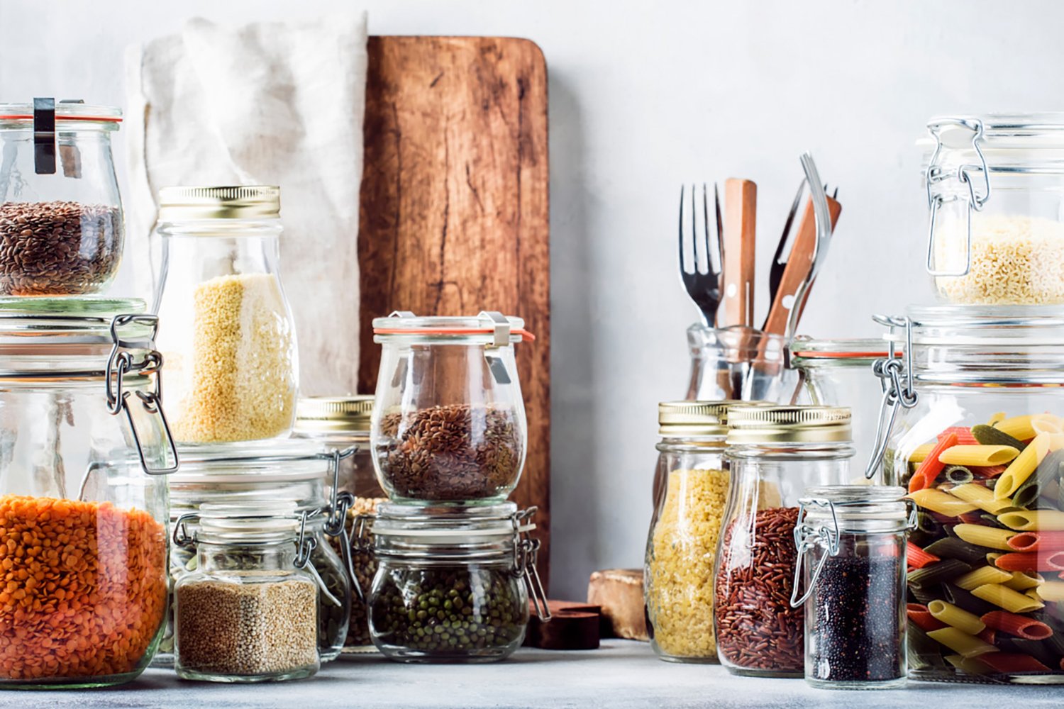 dry food pantry items in pretty glass storage staged in front of a couple of cutting boards and utensils