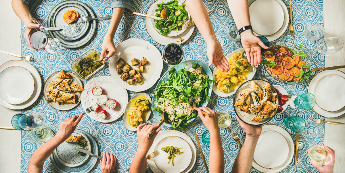 A full table set and guests eating food together using the clean as you go method. 