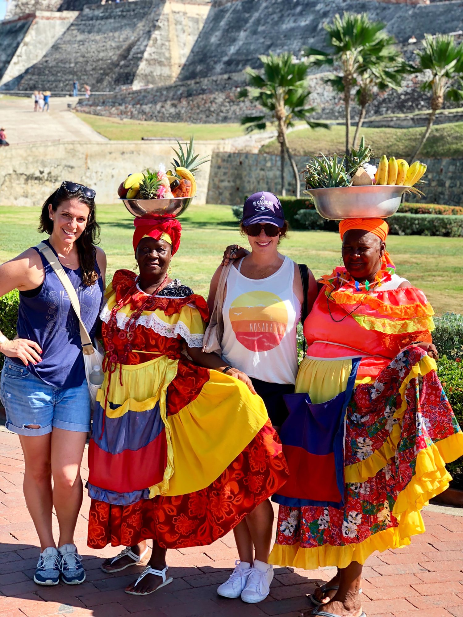 Two female tourists with two indigenous women in traditional dress.