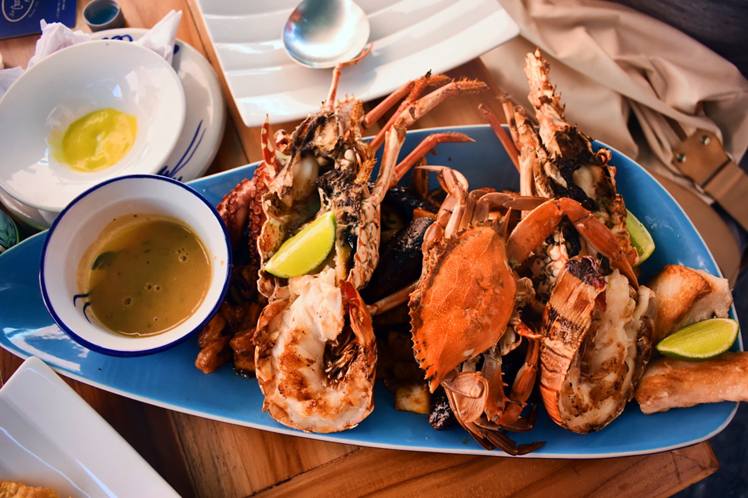 cooked crabs on a blue oblong plate with a dipping sauce