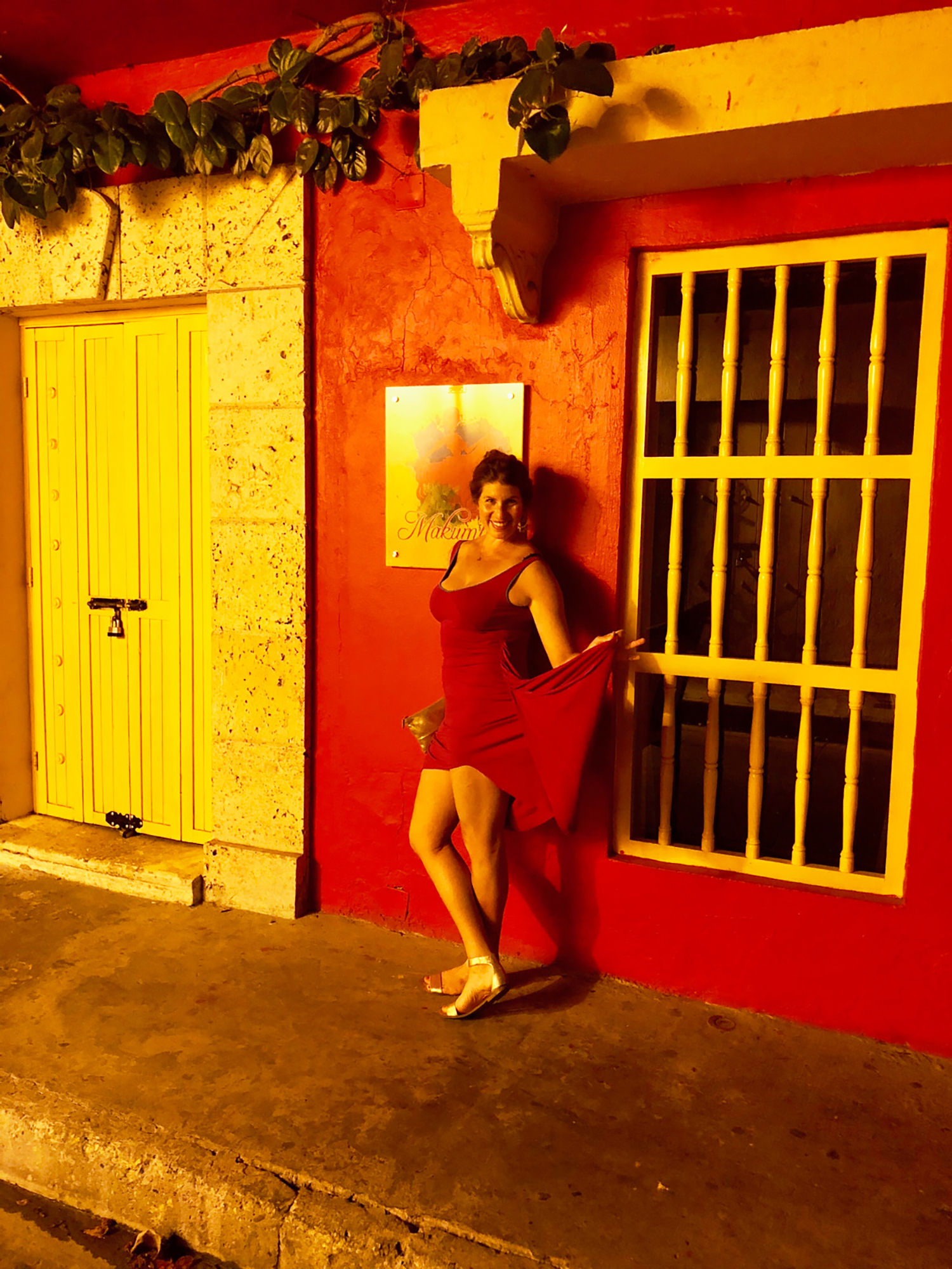 woman at night in a red dress against a red wall out on the town