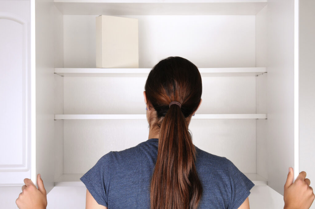 Woman cleaning out a pantry, preparing for a complete reorganization and pantry organization system.