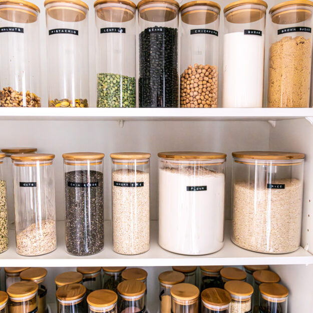 Labeled pantry items stored in same-sized canisters, with spices neatly decanted into matching containers.