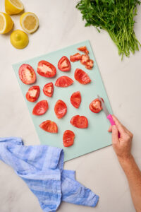 : Hand quartering Roma tomatoes and scooping seeds and membrane with a paring knife.