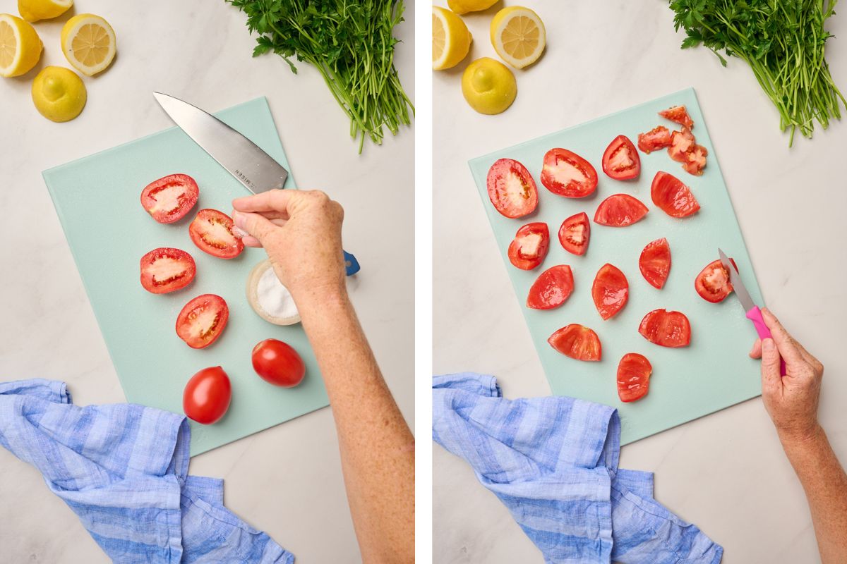 Hand salting Roma tomatoes to remove excess moisture and cutting Roma tomatoes on a blue cutting board with parsley, lemons, and a chef’s knife on the side.