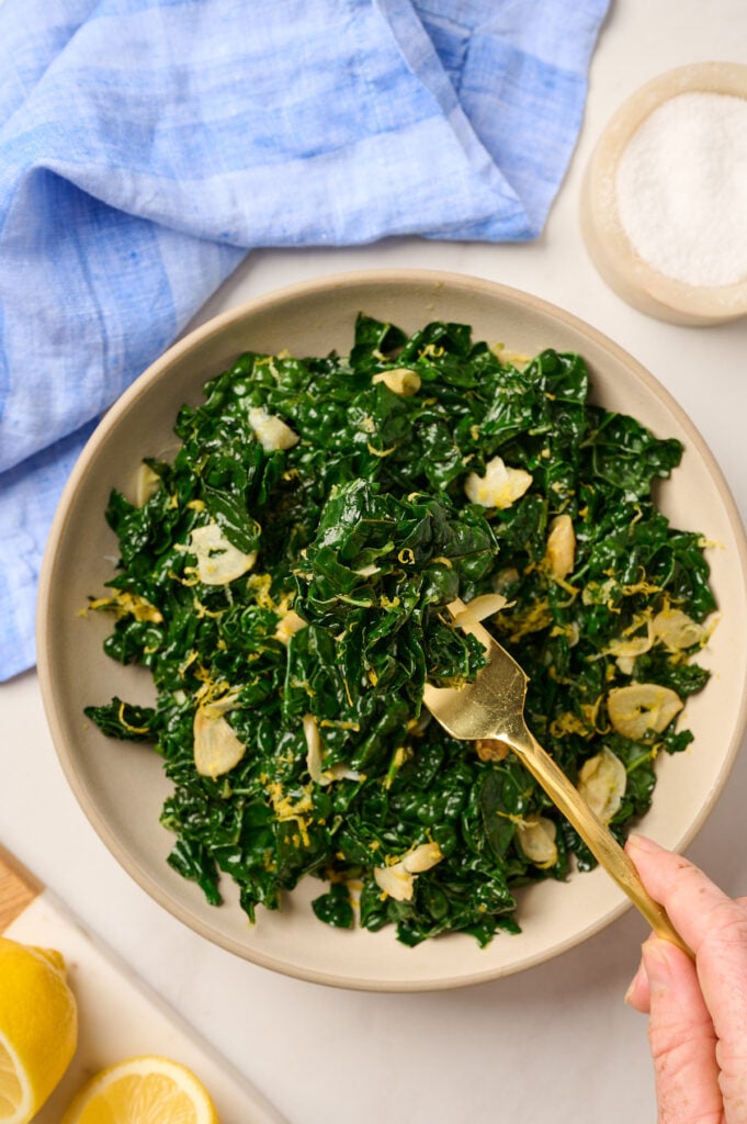 Close-up of kale on a gold fork over a bowl with blue linen underneath