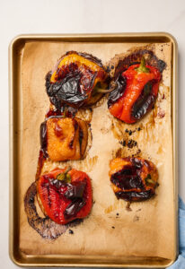 Oven-roasted peppers on a tray and flame-roasted with blackened skins.