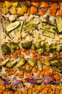 Roasted vegetables on a baking sheet with browned edges and caramelized color