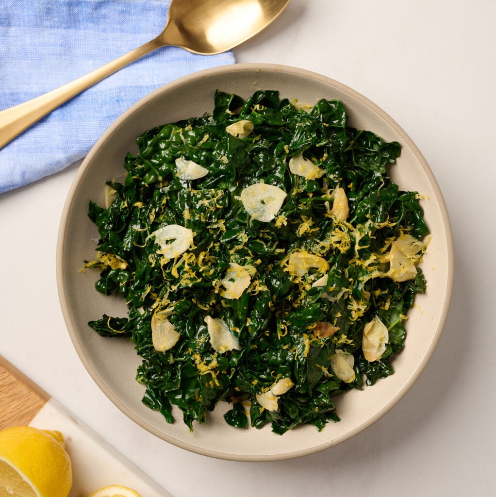 Cooked kale served in a bowl and topped with fresh lemon zest