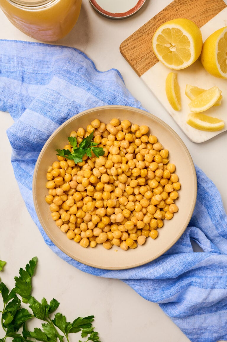Finished bowl of tender chickpeas with lemon wedge and reserved broth jar