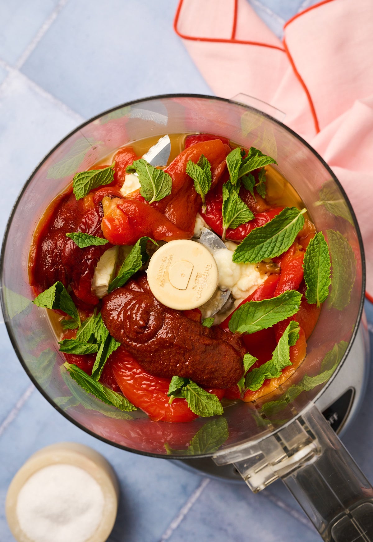 All tirokafteri ingredients in a food processor ready to blend, including harissa and fresh mint