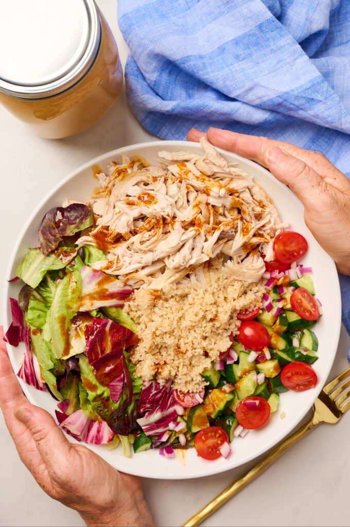 Shredded chicken served in a grain bowl with greens and vegetables