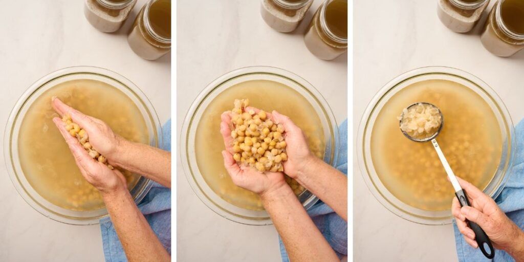 Cooked chickpeas in bowl of water with hands rubbing off skins and skimming them